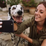 Eine Frau filmt mit ihrem Handy sich selbst und ihren Dalmatiner.