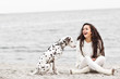 Happy young woman resting at beach in autumn with dog