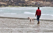 Un homme tient son chien en laisse sur la plage de Trestel